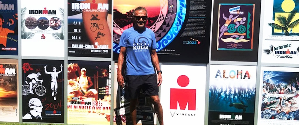 Ironman competition swimmer standing in front of a sponsor board.